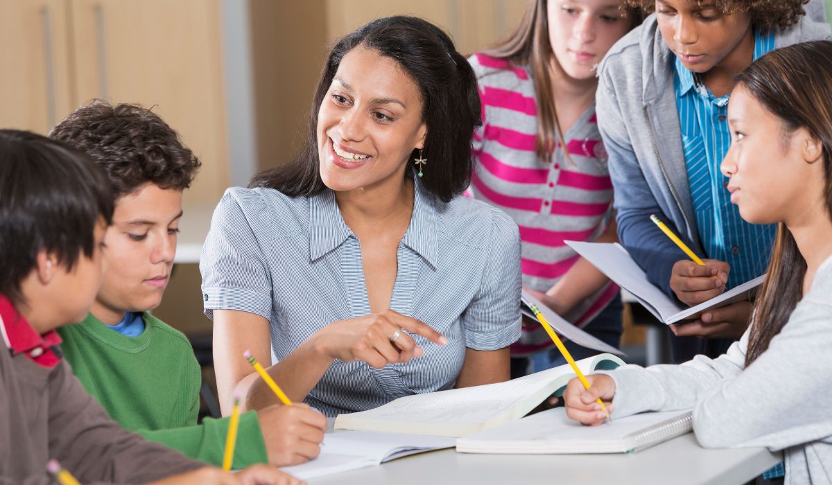 A teacher is surrounded by numerous students.